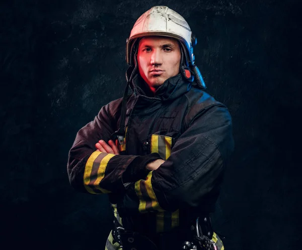 Brutaler Feuerwehrmann in Uniform posiert mit verschränkten Armen und selbstbewusstem Blick für die Kamera. — Stockfoto