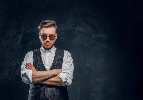 Elegantemente vestido hombre en gafas de sol posando contra una pared de textura oscura — Foto de Stock