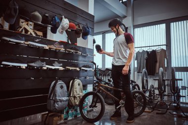 Bir mağazada yeni spor ayakkabıları seçerek motosikletini ile ayakta genç adam.