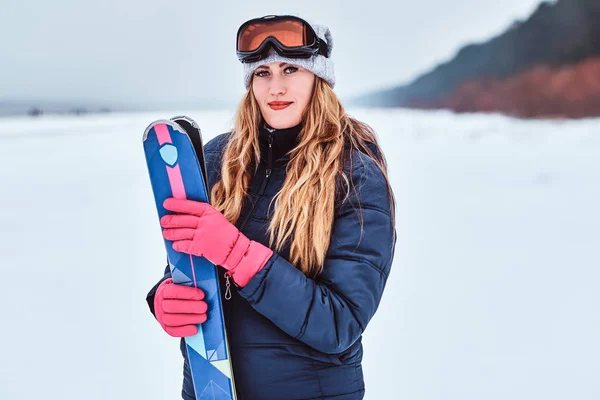 Karlı bir plajda kayaklar ile poz sıcak giysiler giyen Norveçli kadın — Stok fotoğraf