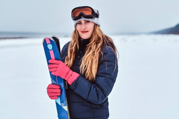 Mulher norueguesa vestindo roupas quentes posando com esquis em uma praia nevada — Fotografia de Stock