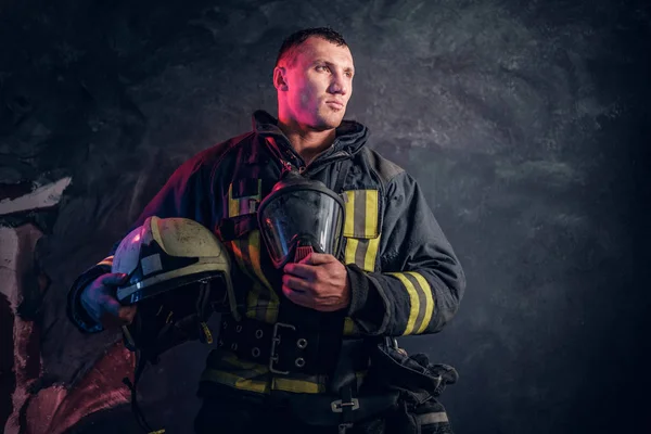 Portrait of a fireman in uniform holding a helmet and oxygen mask — Stock Photo, Image
