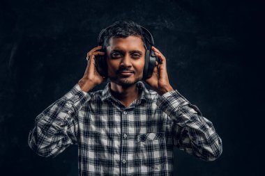 Yakışıklı olan Hint müzik kablosuz kulaklık karanlık bir stüdyoda ayakta mutlu dinlemek olduğunu