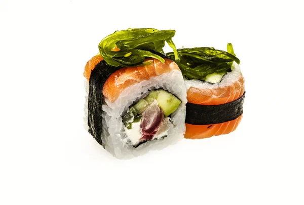 Rollo japonés envuelto en una rebanada delgada de salmón y adornado con algas marinas . — Foto de Stock