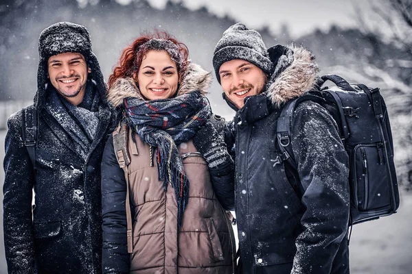 Eine Gruppe von Freunden steht nebeneinander und blickt inmitten eines verschneiten Waldes in die Kamera — Stockfoto