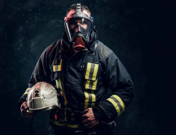 Portrait of a male in full firefighter equipment posing in a dark studio — Stock Photo, Image