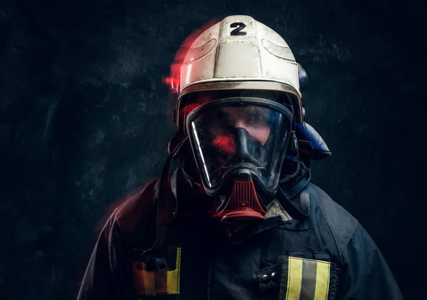 Portrait of a firefighter in safety helmet and an oxygen mask in dark studio — Stock Photo, Image