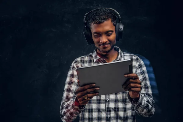 Ινδική άντρας σε ασύρματα ακουστικά, βλέποντας μια ταινία για το tablet στο studio — Φωτογραφία Αρχείου