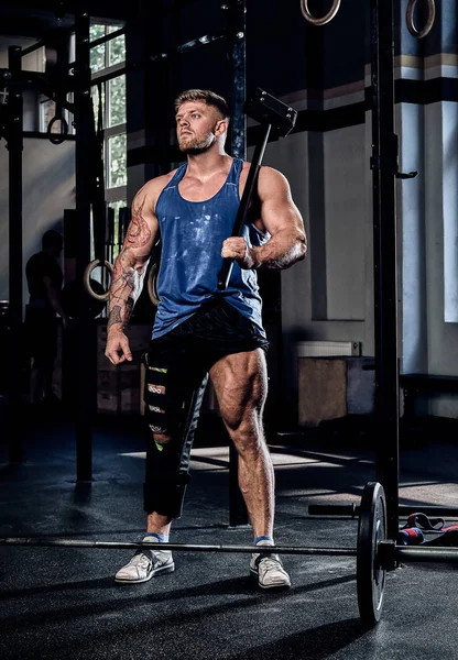 Powerlifter professionnel avec un bandage sur une jambe, tenant un marteau de sport, échauffement avant entraînement, récupération des blessures . — Photo