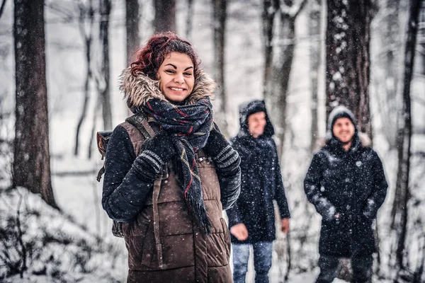 Menina ruiva com amigos caminhar no inverno na floresta — Fotografia de Stock