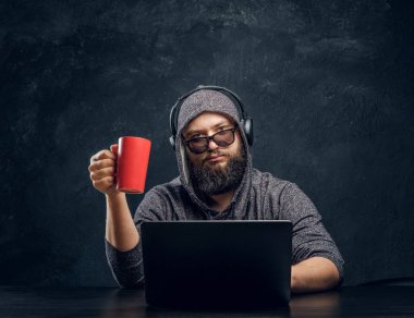 Bir hacker bir dizüstü bilgisayar ve bir fincan kahve karanlık bir odada tutan arkasına oturur... ve dikkatle kameraya bakıyor