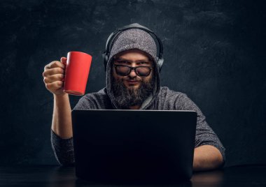 Bir hacker bir dizüstü bilgisayar ve bir fincan kahve karanlık bir odada tutan arkasına oturur... ve dikkatle kameraya bakıyor