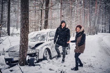 Ormanın içinde karlı bir yol ağaca çarpmışlar kız arkadaşı, adam gülüyor