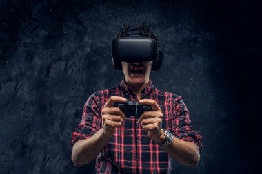 Duygusal adam VR kulaklık kullanarak ve joystick ile bilgisayar oyunu bir stüdyoda karanlık duvar arka plan karşı oynamak.