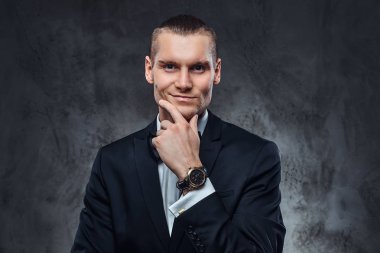 Zarif siyah Klasik takım ve papyon, yüzünü dokunaklı ve bir kameraya bakarak yakışıklı adam kılığında. Stüdyo karanlık dokulu duvara vurdu