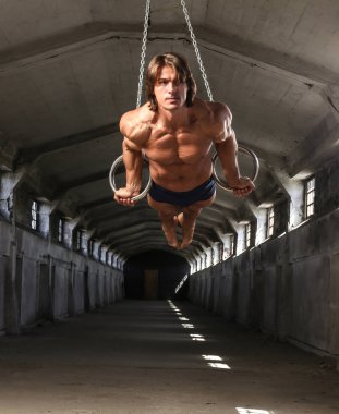 Profesyonel bir sporcu ile güzel bir kaslı vücudu terk edilmiş Endüstriyel Bina içinde jimnastik yüzük tren