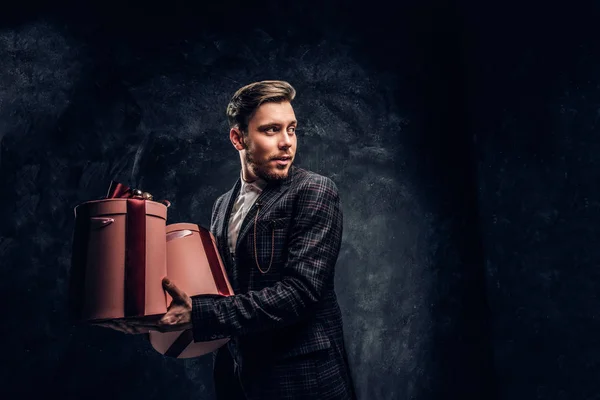 Elegantně oblečený muž drží dary při pózování v temné studio — Stock fotografie