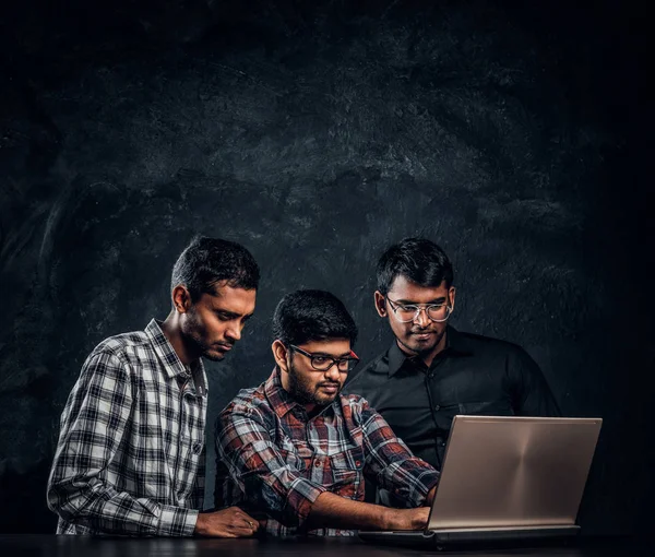 Bir dizüstü bilgisayar ile masada bekleyen birlikte bir proje üzerinde çalışan üç Hint öğrenciler — Stok fotoğraf