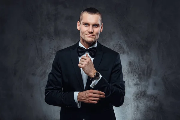 A handsome man in black suit fastening buttons on the sleeves. — Stock Photo, Image