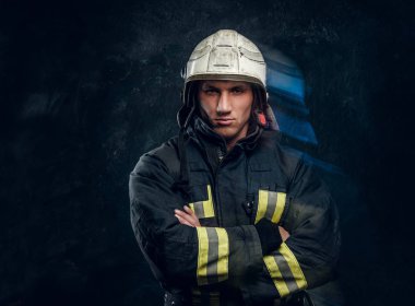 Çapraz kol ve kendinden emin bir görünüm ile kamera ayakta için poz üniformalı acımasız itfaiyeci.