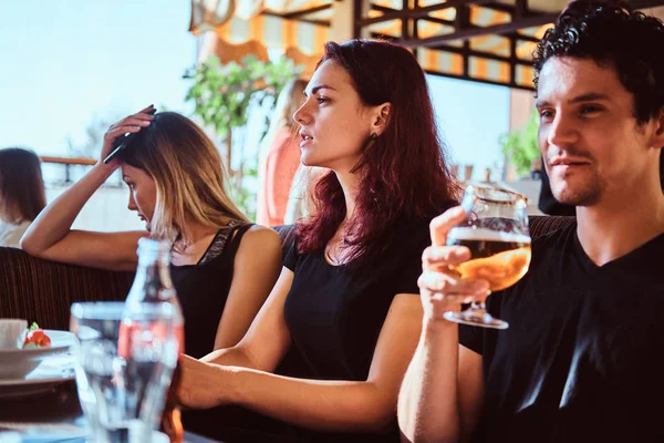 Jóvenes amigos relajarse en el restaurante o cafetería al aire libre, beber cerveza y hablar — Foto de Stock