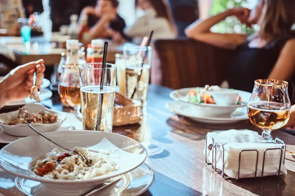 Los amigos cenan en el café al aire libre. Imagen de cerca de una mesa con diferentes platos y bebidas — Foto de Stock