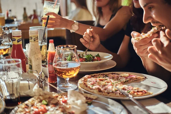 Unga vänner eleverna äter pizza och sallader i en utomhus caf under lunchrast — Stockfoto