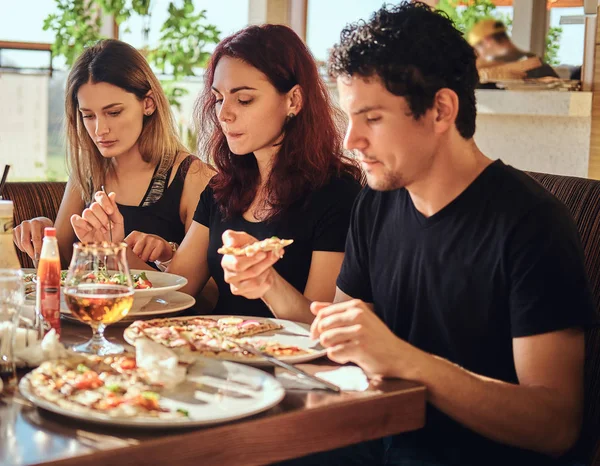 Hora de la pizza. Jóvenes amigos disfrutando de pizza y ensalada en un café al aire libre — Foto de Stock