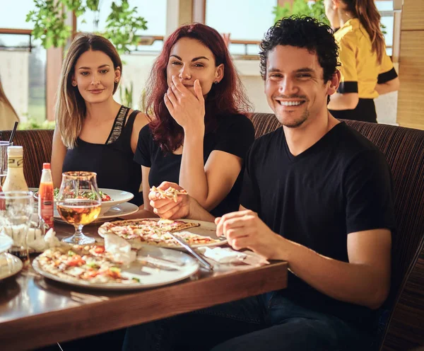 Jóvenes amigos alegres disfrutando de la comida y divirtiéndose juntos en el restaurante o cafetería al aire libre — Foto de Stock