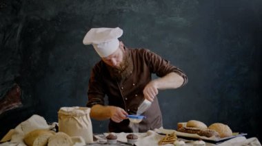 Profesyonel şef taze çörek stüdyoda hazırlanan pudra şekeri serpilir