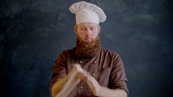 Chef-kok zijn handen schudt en meel vliegt van hen, dan kruist zijn handen en een glimlach op de camera — Stockvideo