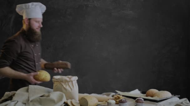 Chef coloca pão recém-assado em uma bandeja de cozimento, decorando a mesa com doces de sua padaria — Vídeo de Stock