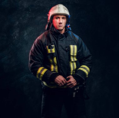 Portrait of firefighter dressed in uniform and safety helmet looking sideways with a confident look clipart