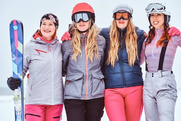 Mujeres alegres amigas en deportes ropa de invierno con esquís posando —  Fotos de Stock
