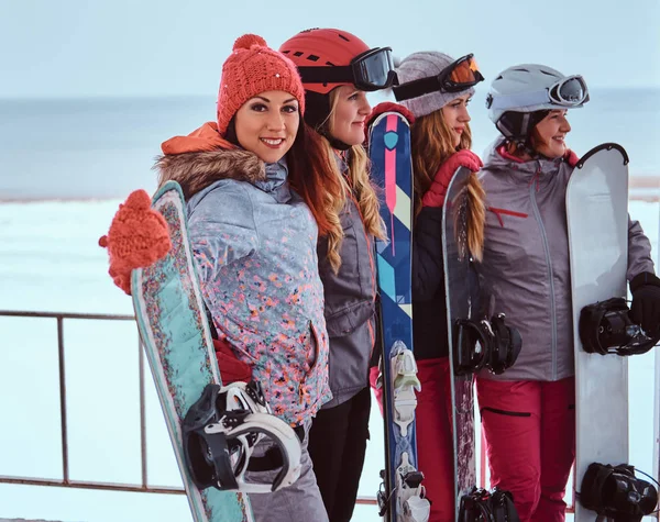 Πλευρά άποψη πορτρέτο του γυναίκες φίλους στο σπορ χειμερινά ρούχα κρατώντας σνόουμπορντ — Φωτογραφία Αρχείου