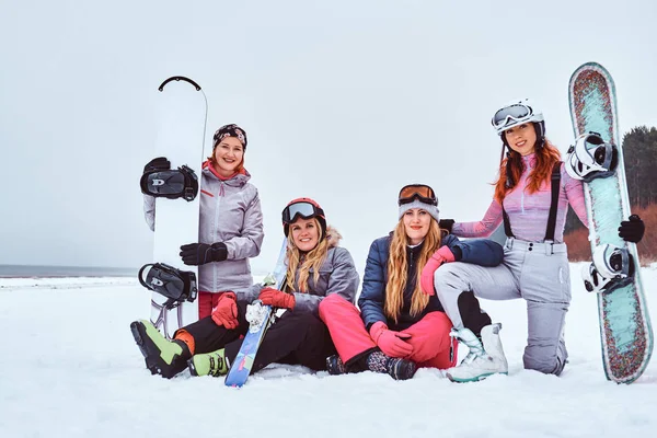 Mulheres alegres amigos em esportes roupas de inverno com snowboards e esquis abraçando juntos — Fotografia de Stock