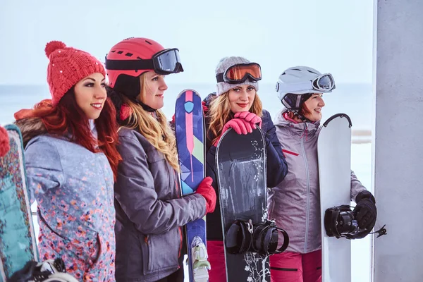 Femei vesele prieteni în sport haine de iarnă cu snowboards și schiuri îmbrățișându-se împreună — Fotografie, imagine de stoc