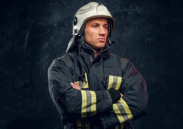 Жорстокий пожежник у формі позування для камери, що стоїть з схрещеними руками і впевнено дивиться . — стокове фото