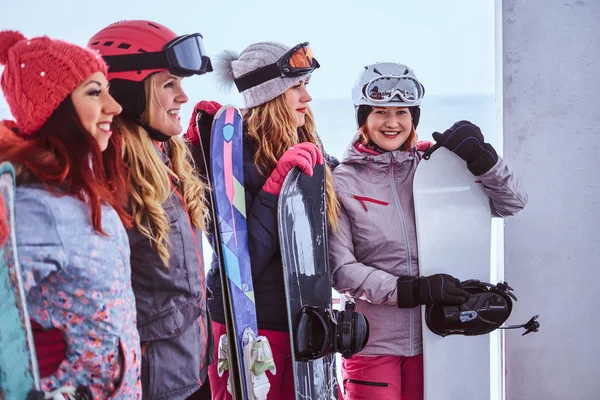Retrato vista lateral de una mujer amiga en ropa deportiva de invierno sosteniendo tablas de snowboard —  Fotos de Stock