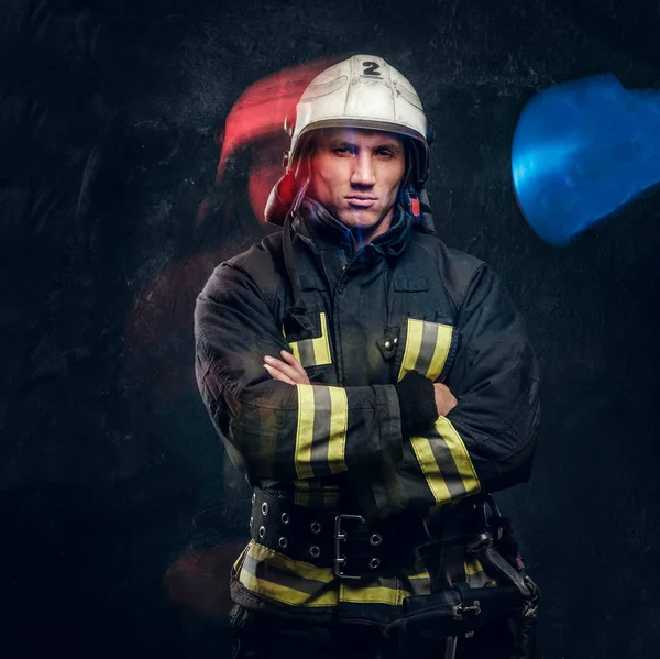 Brutal fireman in uniform posing for the camera standing with crossed arms and confident look.