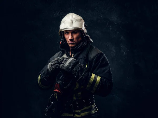 制服・安全ヘルメット暗いスタジオでポーズの消防士 — ストック写真