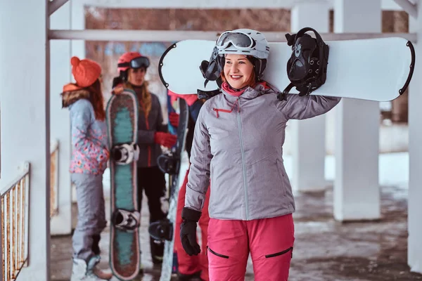 Roșcată femeie purtând îmbrăcăminte sport de iarnă pozând cu un snowboard — Fotografie, imagine de stoc