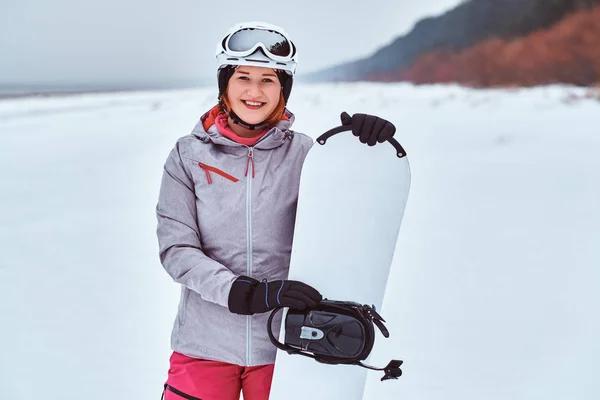 Chica noruega vistiendo traje de snowboard caliente, posando con su snowboard — Foto de Stock