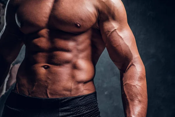 Close-up image of muscular torso with dark wall background — Stock Photo, Image