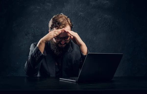 Moe bebaarde programmeur zitten aan de tafel met laptop in kantoor — Stockfoto