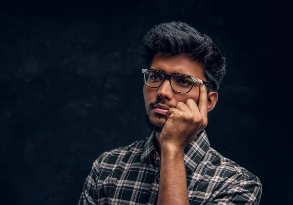 Nadenkend Indiase studenten dragen brillen en een plaid shirt. — Stockfoto