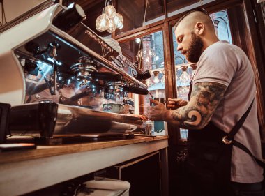 Dövmeli barista şık sakal ve saç modeli bir kafe ya da Restoran bir kahve makinesinde çalışma ile