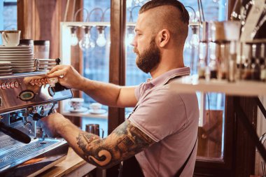 Dövmeli barista şık sakal ve saç modeli bir kafe ya da Restoran bir kahve makinesinde çalışma ile