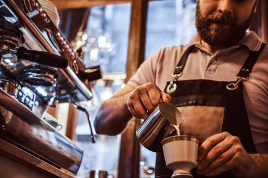 Bir kapuçino, yapım önlük giyen Barista bir restoran veya kahve dükkanı bir fincan süt dökme