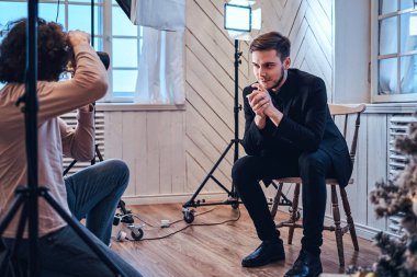  stüdyoda çekim fotoğraf: yakışıklı genç bir adam oturuyor, gülümseyen ve poz